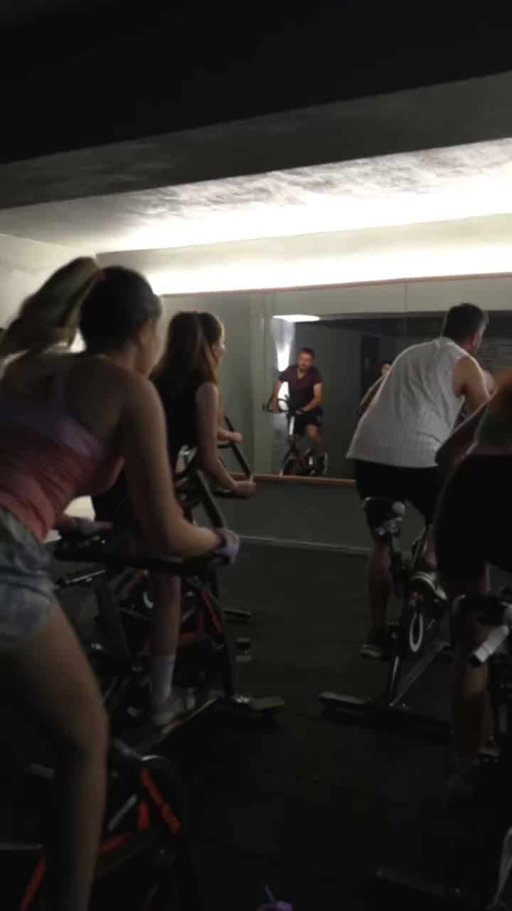 Karanlık stüdyoda spin bisikletlerinde pedal çeviren grup