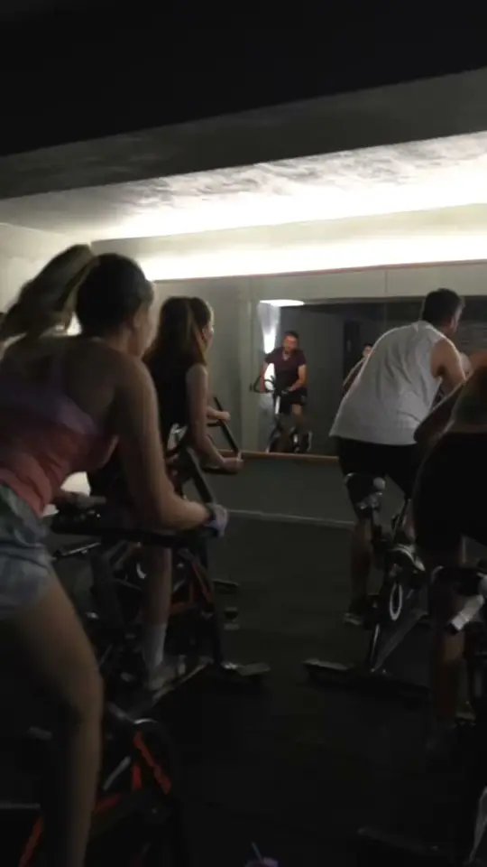 Karanlık stüdyoda spin bisikletlerinde pedal çeviren grup